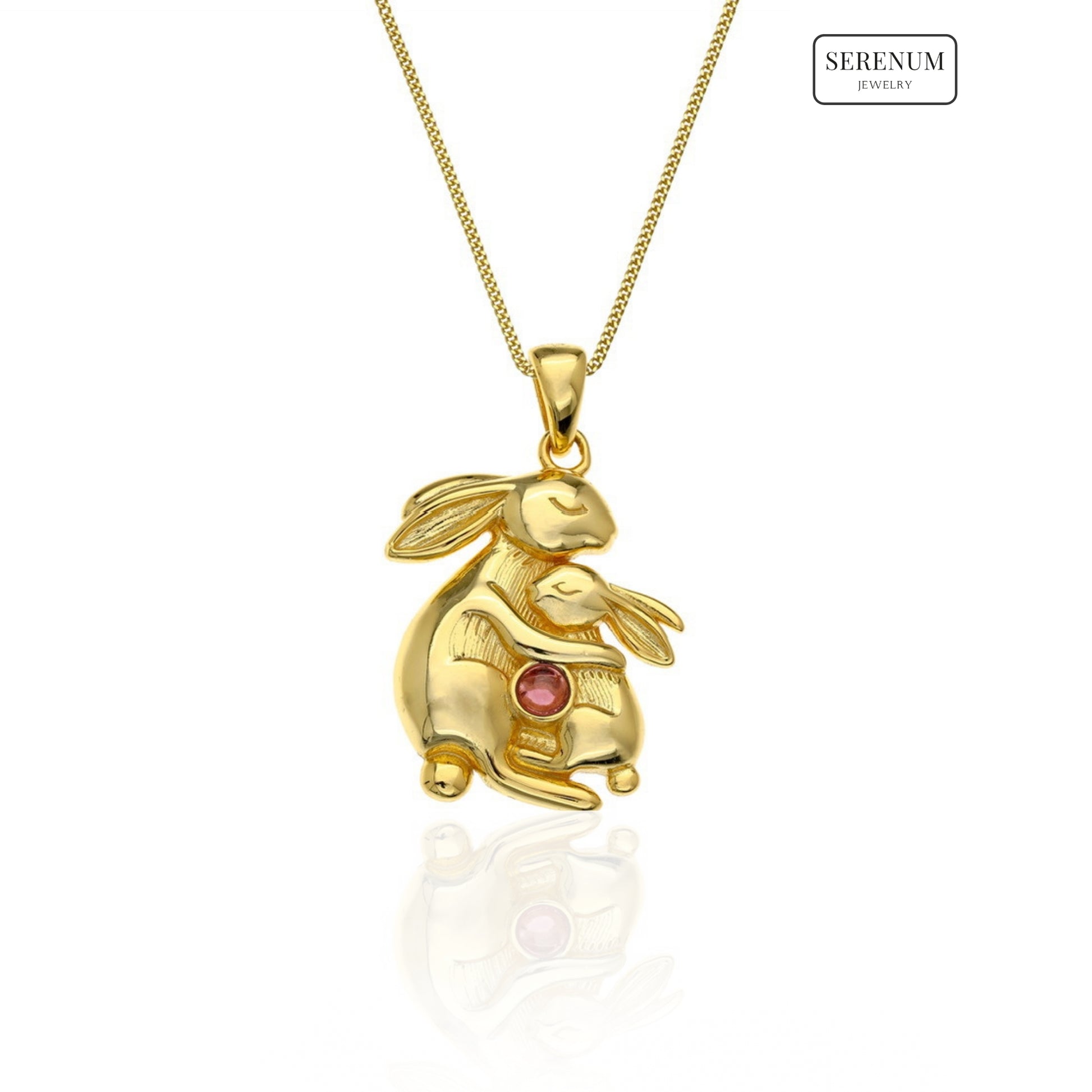 Gold rabbit-shaped pendant with a red gemstone on a white background, branded 'Serenum'.